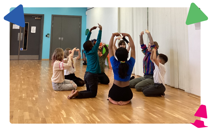 A group of boys and girls sitting on the dance studio floor practicing some mindfulness stretching.